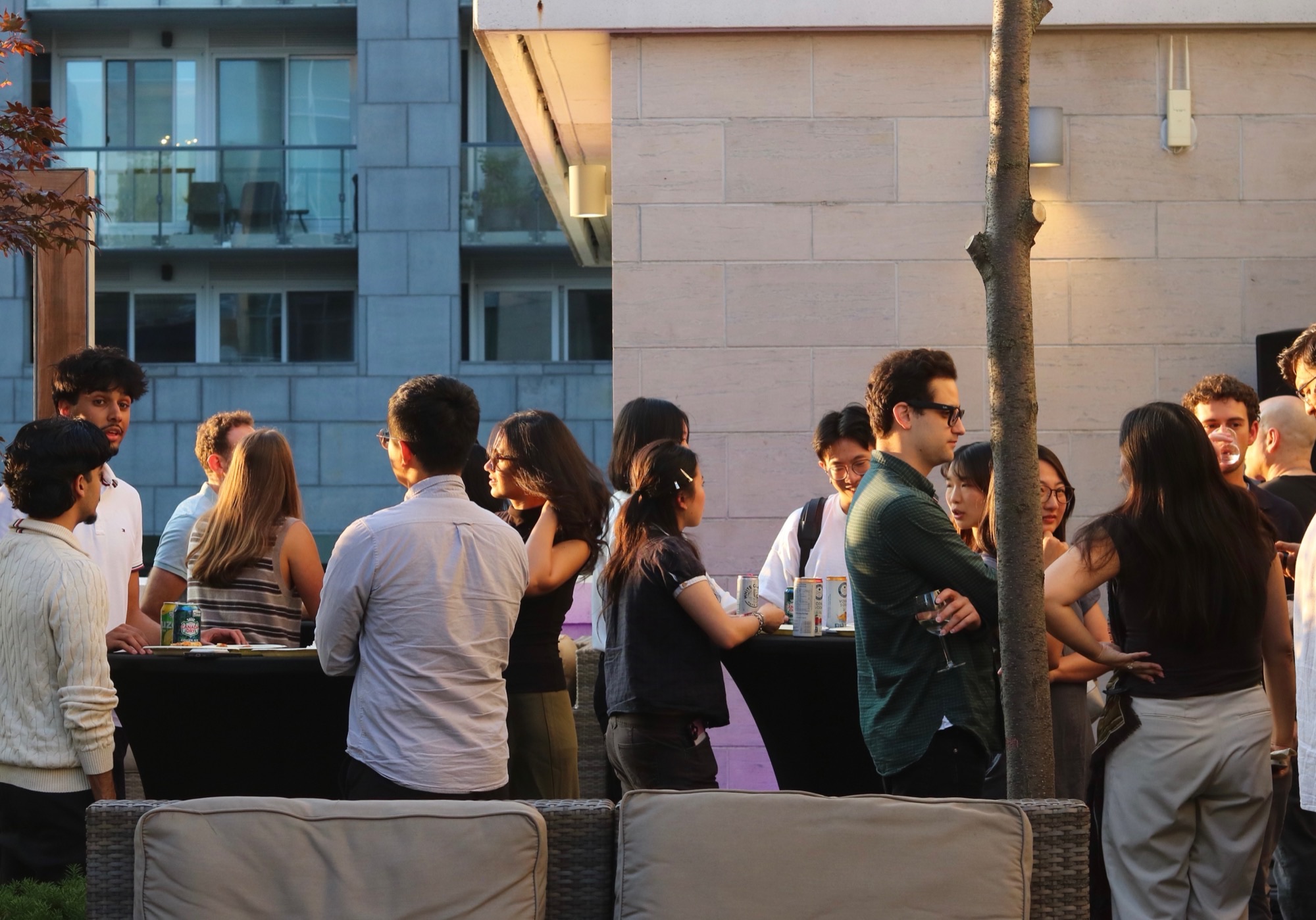 Emerging Investors Canada members talking in small groups around drinks tables at an outdoor evening social.